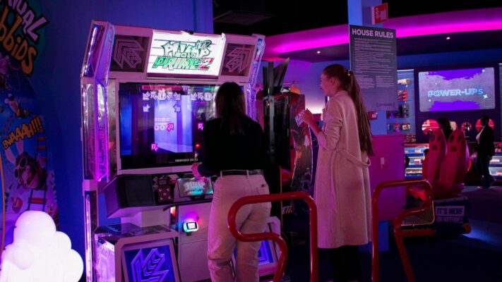 Twee personen spelen een dansspel in een arcadehal, waarbij muziek en ritme centraal staan