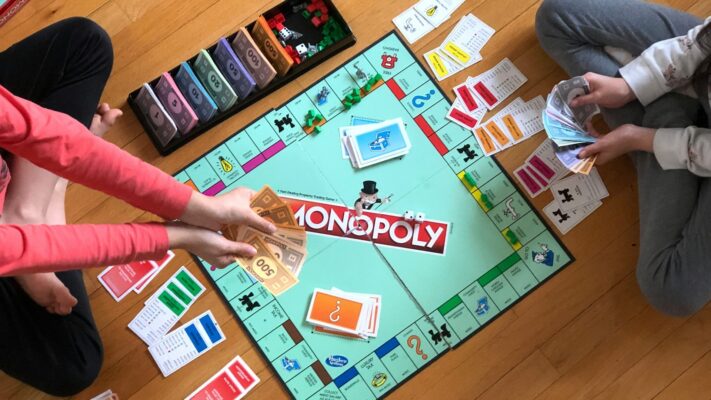 Monopoly bord op de vloer met spelers, klassiek voorbeeld van bordspellen volwassenen samen